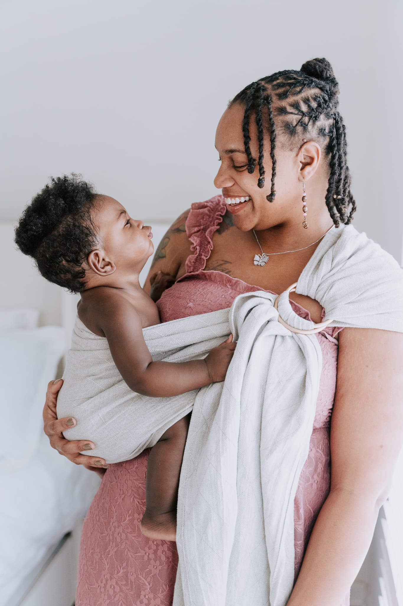 Divinity Doula founder Jernae Webb smiling as she holds her newborn in a white wrap.